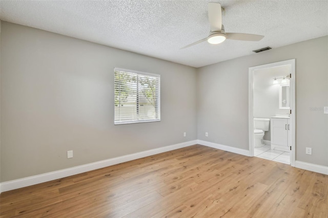 unfurnished bedroom with ceiling fan, ensuite bathroom, light hardwood / wood-style floors, and a textured ceiling