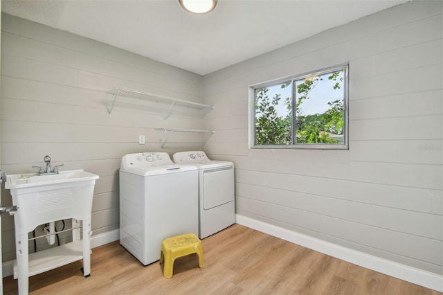 laundry area with washing machine and clothes dryer and light hardwood / wood-style flooring