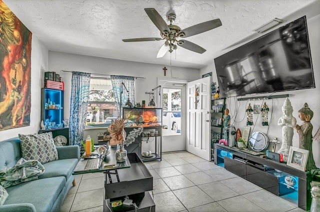 living room with ceiling fan, a textured ceiling, and light tile patterned flooring