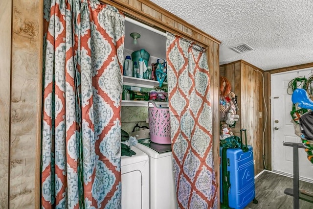 laundry area featuring washing machine and dryer, wooden walls, and a textured ceiling