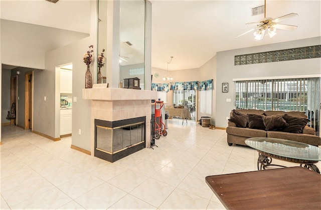 living room with ceiling fan with notable chandelier, light tile patterned flooring, and a fireplace