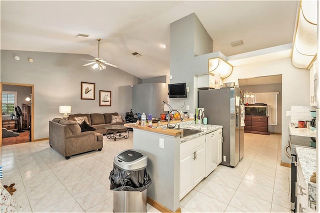 kitchen with appliances with stainless steel finishes, sink, white cabinets, light tile patterned floors, and light stone countertops