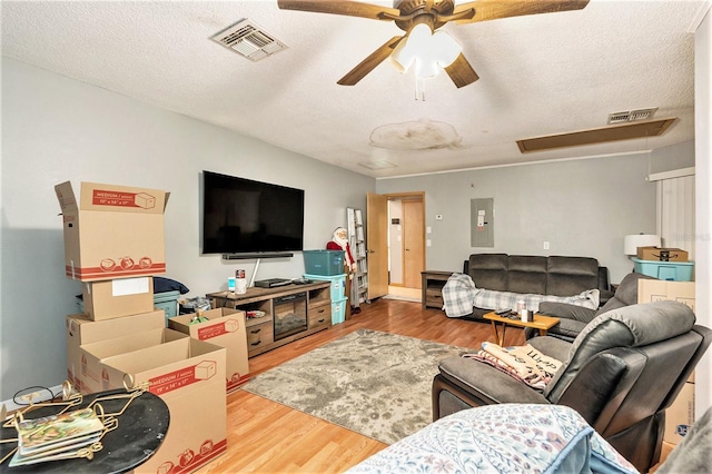 living room featuring electric panel, ceiling fan, hardwood / wood-style floors, and a textured ceiling