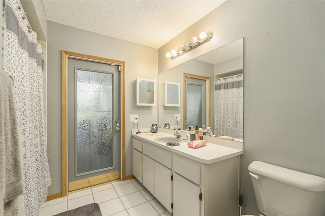 bathroom with a textured ceiling, toilet, vanity, and tile patterned flooring