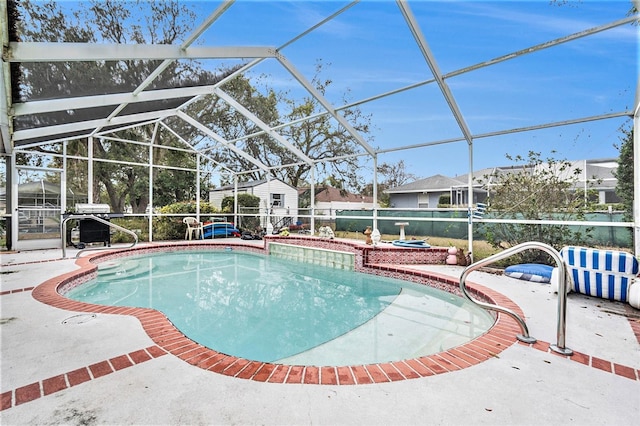 view of swimming pool featuring glass enclosure, a shed, and a patio