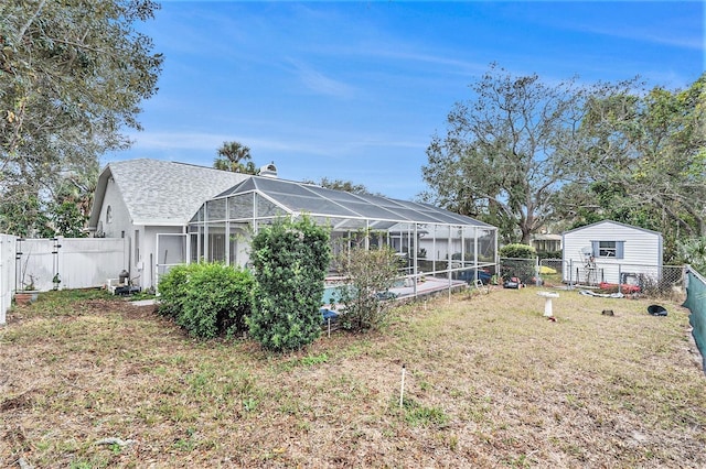 back of property featuring glass enclosure, a yard, and a swimming pool