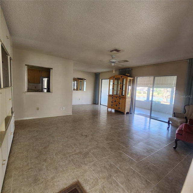 unfurnished living room with ceiling fan, visible vents, and a textured ceiling