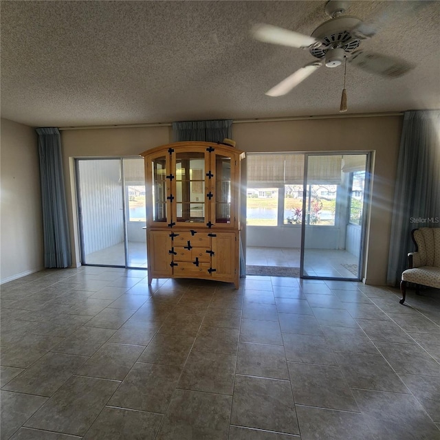 unfurnished living room with a textured ceiling, plenty of natural light, and a ceiling fan