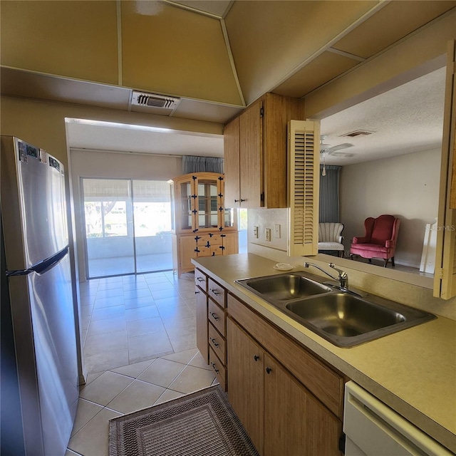 kitchen featuring visible vents, freestanding refrigerator, white dishwasher, light countertops, and a sink