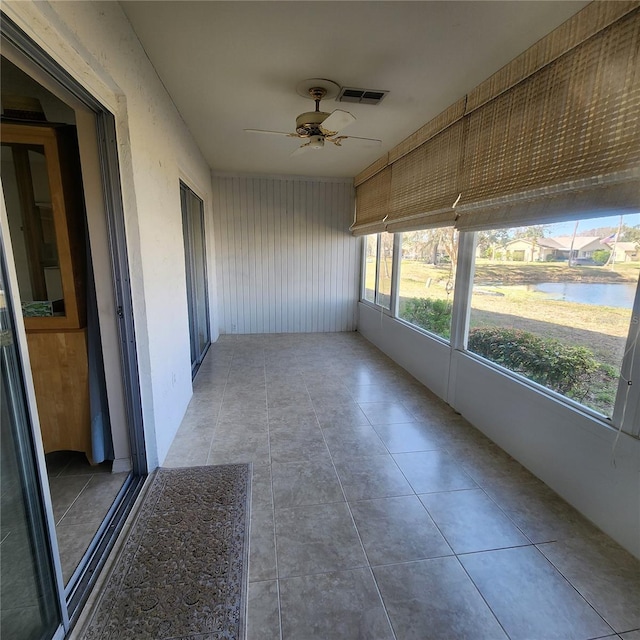 unfurnished sunroom featuring visible vents, ceiling fan, and a water view