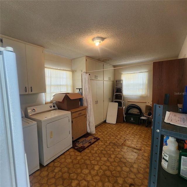 clothes washing area with cabinet space, plenty of natural light, washing machine and clothes dryer, and tile patterned floors