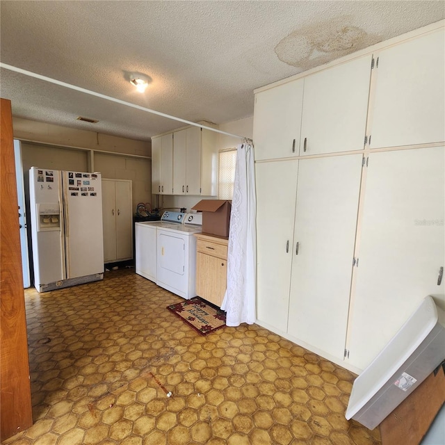 kitchen featuring white refrigerator with ice dispenser, white cabinets, independent washer and dryer, and tile patterned floors