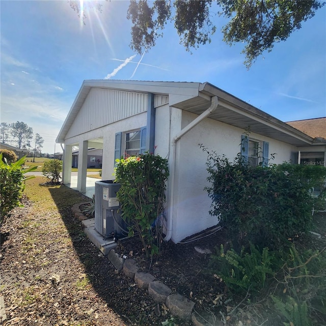 view of side of property with central AC and stucco siding