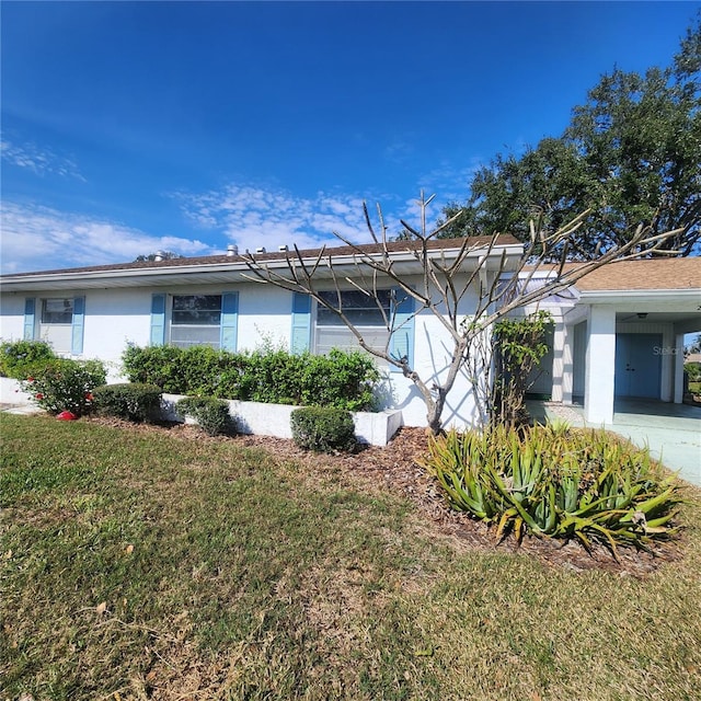 view of home's exterior featuring a carport, a lawn, and stucco siding