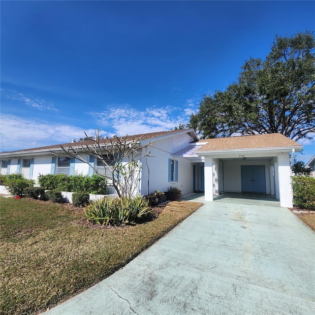 ranch-style house featuring a front yard, concrete driveway, and stucco siding