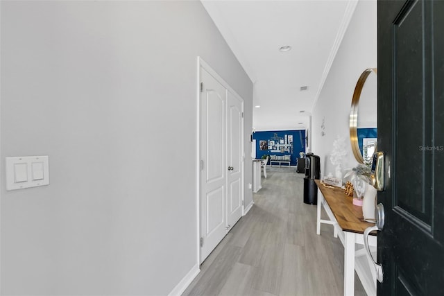 hallway featuring ornamental molding and light hardwood / wood-style floors