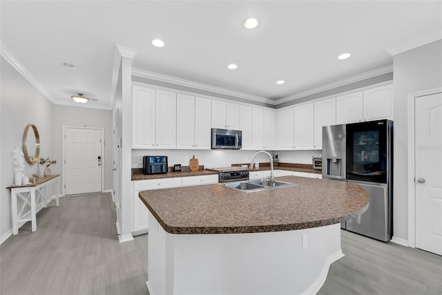 kitchen with sink, appliances with stainless steel finishes, a kitchen island with sink, white cabinetry, and light wood-type flooring