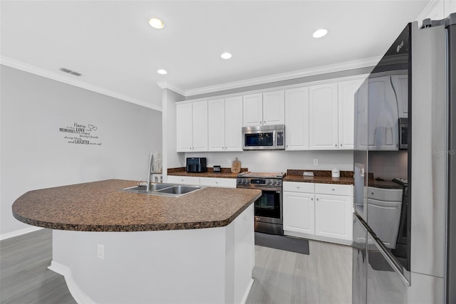 kitchen with white cabinetry, appliances with stainless steel finishes, sink, and a kitchen island with sink