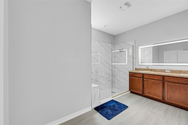 bathroom with vanity, hardwood / wood-style flooring, and tiled shower