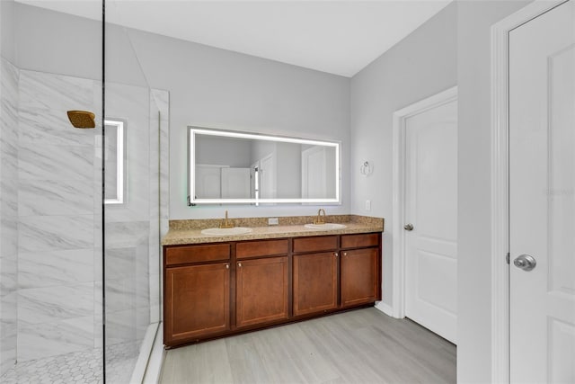 bathroom with hardwood / wood-style flooring, vanity, and a tile shower