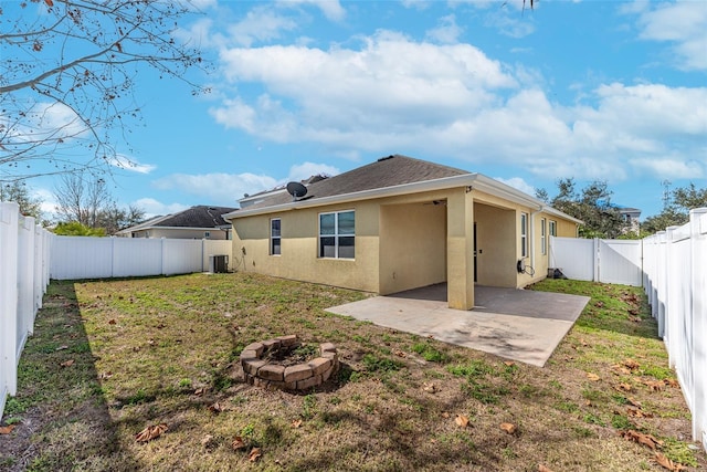 rear view of house with central AC unit, a fire pit, a patio area, and a lawn