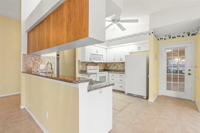 kitchen with kitchen peninsula, white cabinetry, white appliances, dark stone countertops, and decorative backsplash