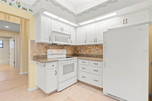 kitchen featuring dark stone countertops, white cabinetry, white appliances, and light tile patterned floors