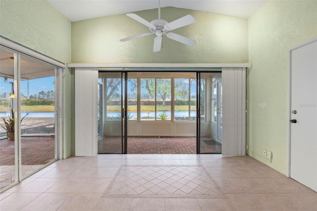 unfurnished room featuring ceiling fan, a water view, light tile patterned floors, and high vaulted ceiling