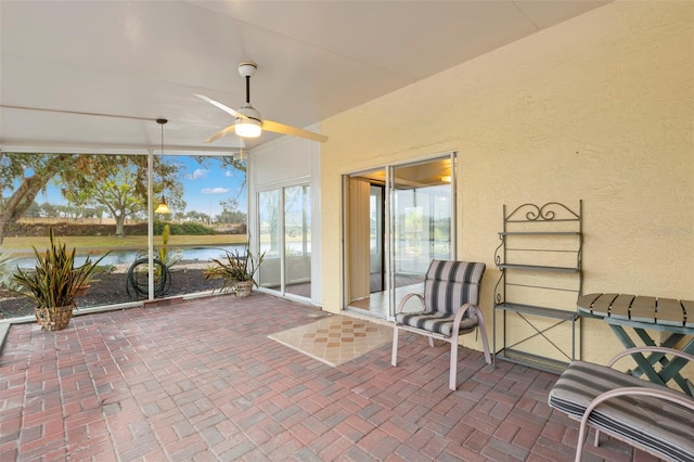 sunroom featuring ceiling fan and a water view