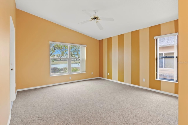 carpeted spare room with ceiling fan, plenty of natural light, and vaulted ceiling