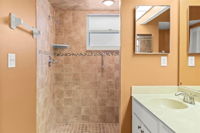 bathroom featuring tiled shower and vanity