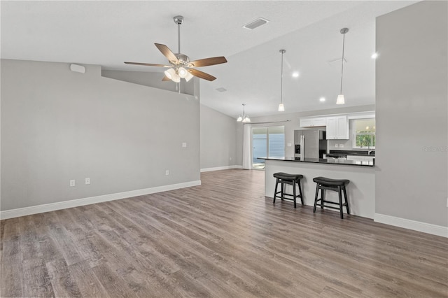 unfurnished living room featuring ceiling fan, wood-type flooring, and lofted ceiling