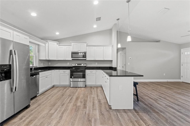 kitchen with appliances with stainless steel finishes, a kitchen breakfast bar, white cabinets, decorative light fixtures, and light hardwood / wood-style flooring