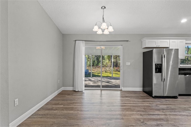 kitchen with a textured ceiling, white cabinets, wood-type flooring, stainless steel appliances, and a chandelier