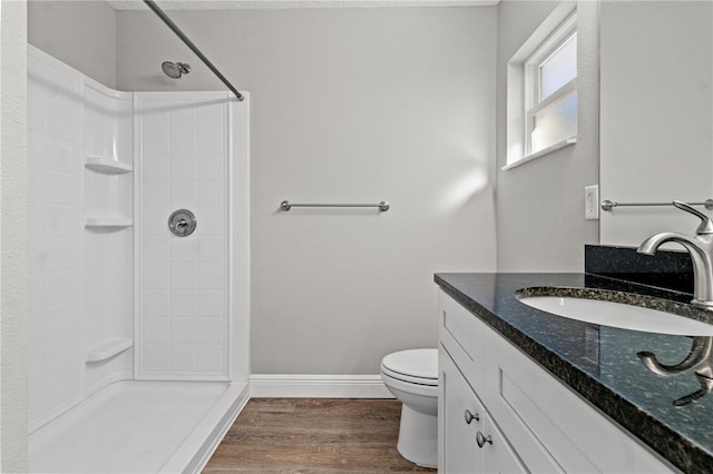 bathroom with hardwood / wood-style floors, toilet, vanity, and walk in shower