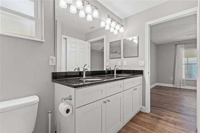 bathroom featuring toilet, a textured ceiling, a wealth of natural light, and vanity