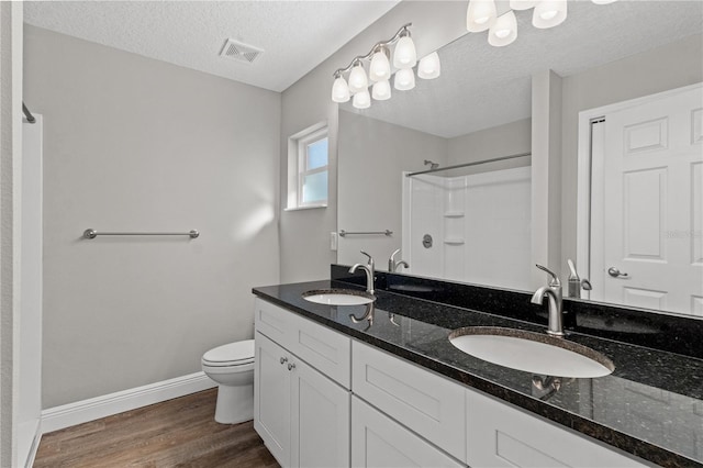 bathroom featuring wood-type flooring, toilet, a textured ceiling, walk in shower, and vanity