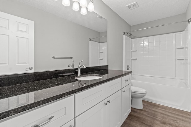 full bathroom with hardwood / wood-style flooring, toilet, a textured ceiling, vanity, and shower / bathtub combination