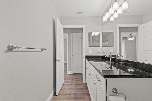 bathroom with vanity, hardwood / wood-style flooring, ceiling fan, and a textured ceiling