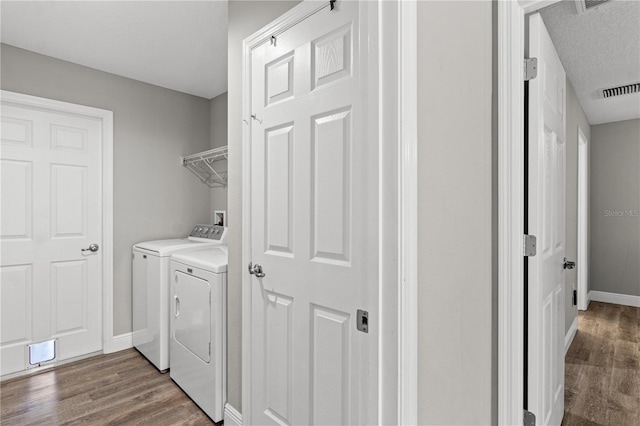 laundry area featuring hardwood / wood-style floors, a textured ceiling, and washer and clothes dryer