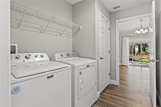 laundry area with wood-type flooring, a chandelier, and washer and dryer