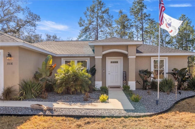 view of front of property featuring roof with shingles and stucco siding