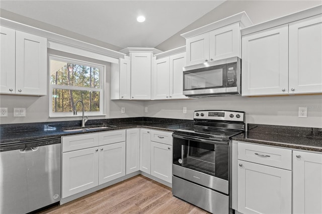 kitchen featuring white cabinetry, lofted ceiling, appliances with stainless steel finishes, and a sink