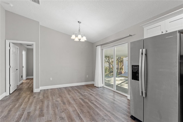 unfurnished dining area featuring baseboards, lofted ceiling, an inviting chandelier, and wood finished floors