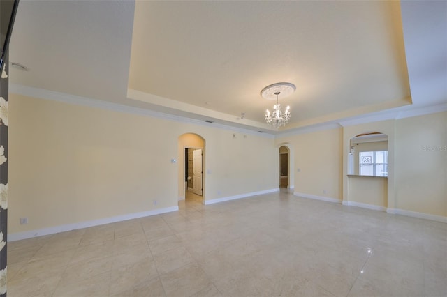 empty room with a notable chandelier, a tray ceiling, and ornamental molding