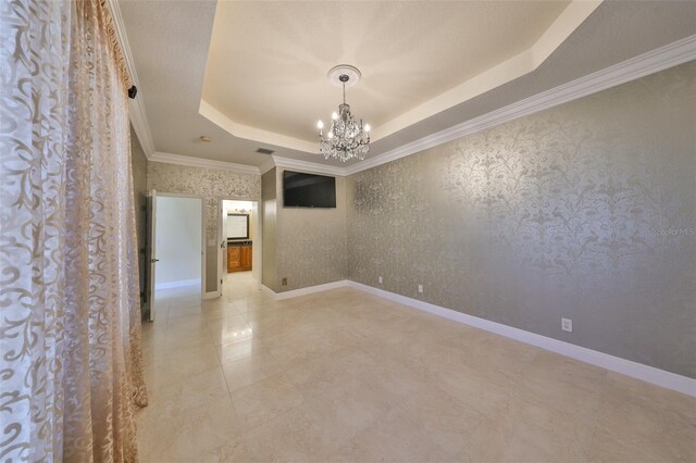 spare room featuring a notable chandelier, a raised ceiling, and ornamental molding