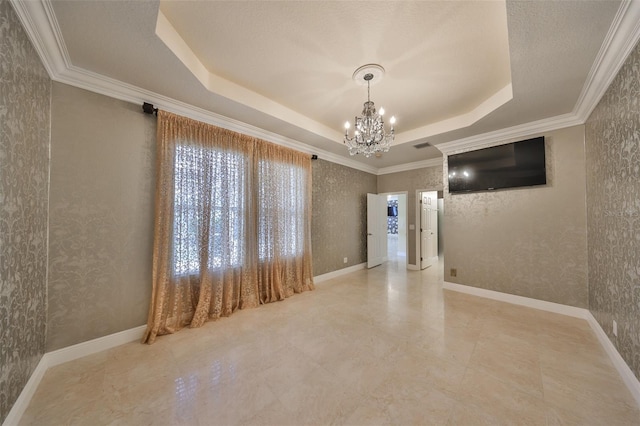 unfurnished room featuring a tray ceiling, ornamental molding, and a notable chandelier