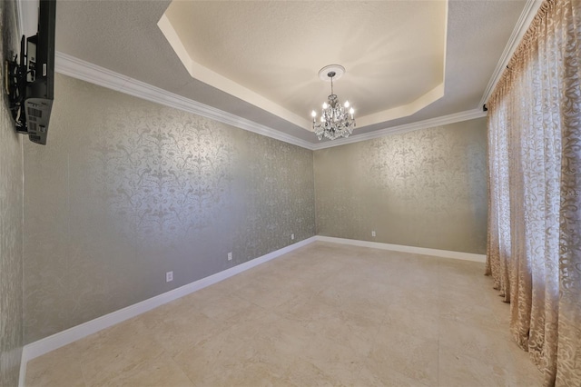 empty room featuring an inviting chandelier, ornamental molding, and a raised ceiling