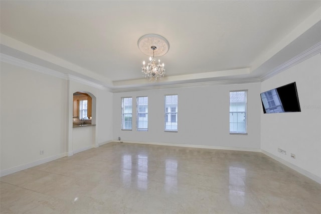 empty room with arched walkways, an inviting chandelier, a tray ceiling, and baseboards