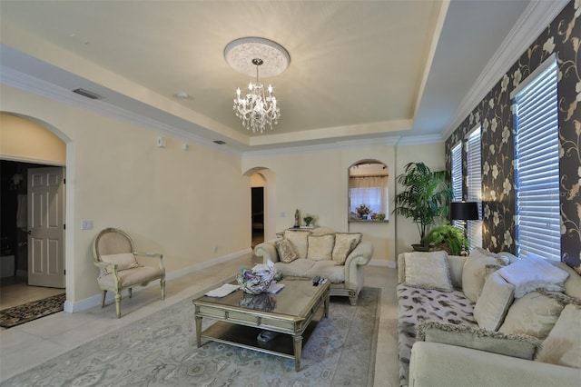 living room with a raised ceiling, visible vents, ornamental molding, arched walkways, and a notable chandelier